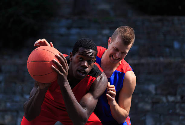 A basketball player strikes an opponent with an elbow.